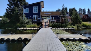 A wooden dock leading to a blue building with a sign reading "WATER RUDDERS". - Hazel Suite - Homer Seaplane Base (Homer)