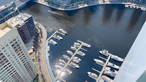 Un port de plaisance où sont amarrés de nombreux bateaux, entouré de grands immeubles et avec un pont en arrière-plan.