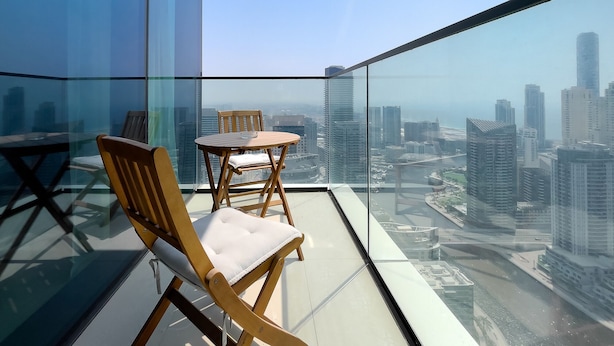 Un balcon doté d’une balustrade en verre donnant sur un paysage urbain.