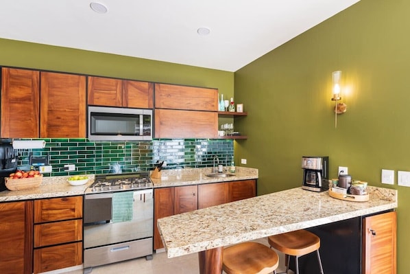 A kitchen with wooden cabinets, a microwave, a stove, and a coffee maker.