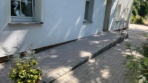 A white building with a paved entrance and a potted plant in the foreground. - Ruhige Unterkunft für 2-3 Personen in Bad Salzungen (Bad Salzungen)