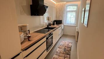 A modern kitchen with a built-in oven, a microwave, and a coffee machine.