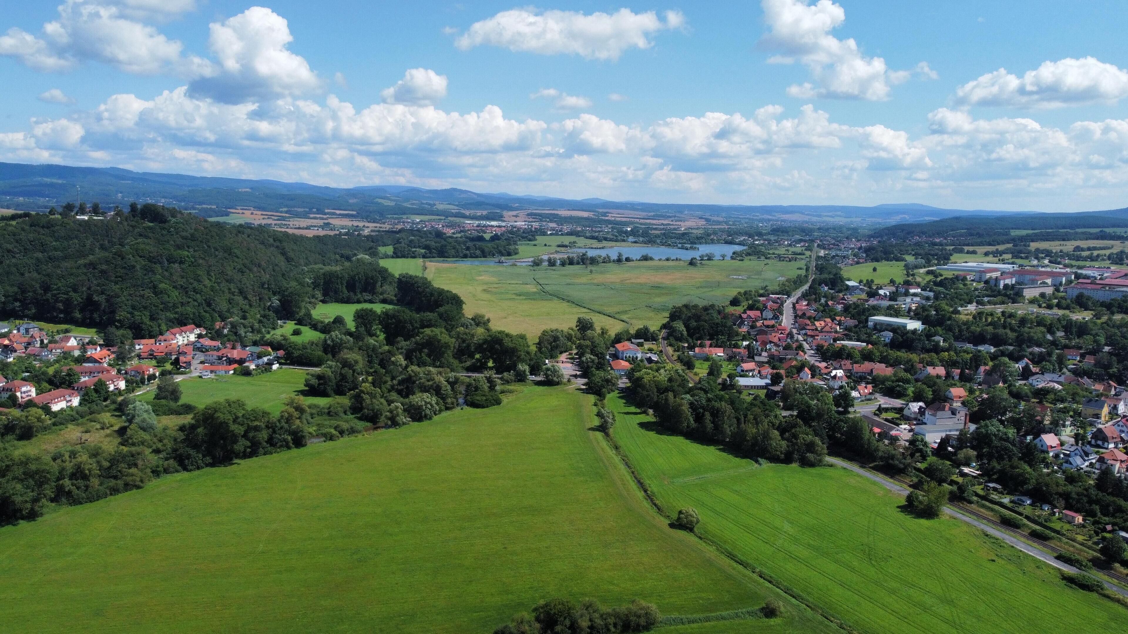 Ländliche Landschaft mit einem Dorf, grünen Feldern und einem See.