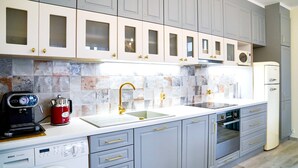Una cocina moderna con armarios grises, encimera blanca, cafetera, lavadora y microondas.