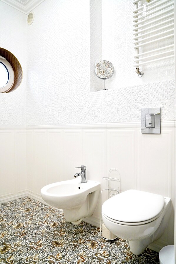 Une salle de bain équipée d’un bidet, de toilettes et d’un miroir.
