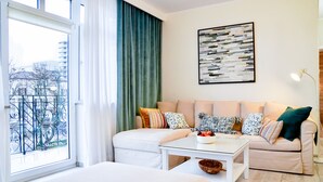 Una sala moderna con un conjunto de sofá, una mesa de centro y vista a la ciudad a través de un ventanal.