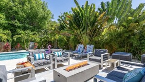 An outdoor lounge area with a pool, lounge chairs, and a fire feature. - Arlington Ocean Oasis 5br 5ba Htd Saltwater Pool (Sarasota)