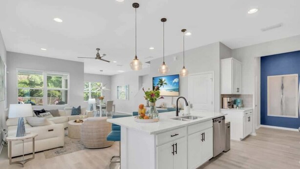 A modern kitchen with white cabinetry, a central island, and pendant lighting. - Arlington Ocean Oasis 5br 5ba Htd Saltwater Pool (Sarasota)