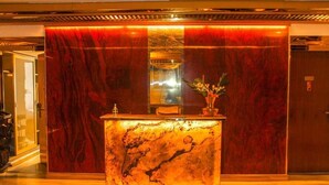 Una zona reception con un bancone in marmo, uno specchio e un vaso con fiori.