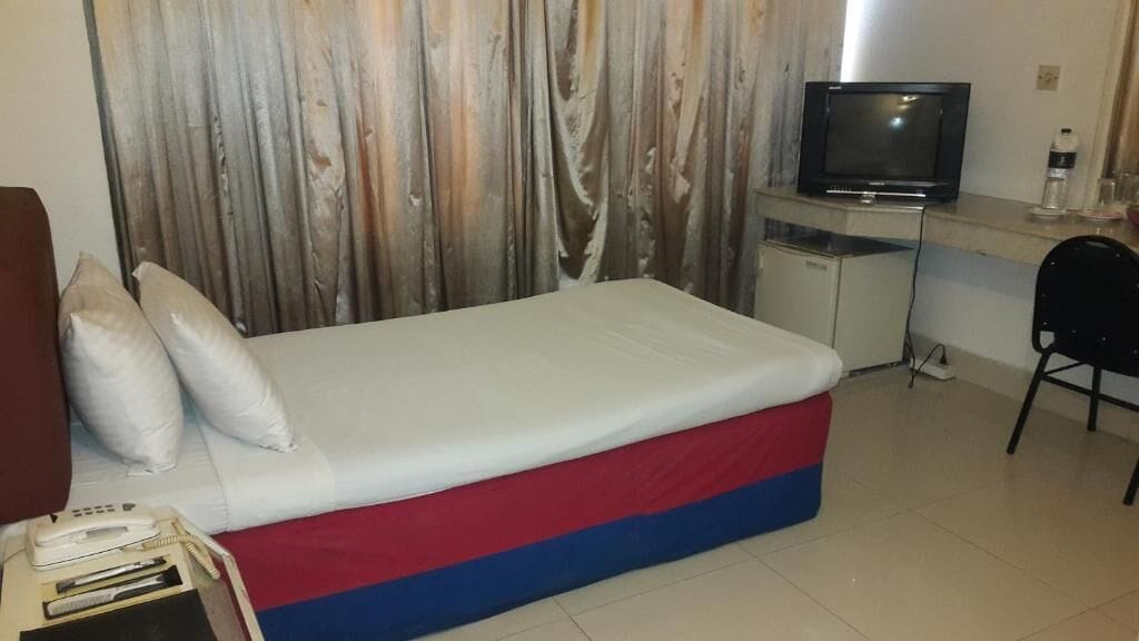 A hotel room with a bed, a desk, a television, and a chair.
