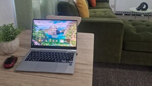 A laptop on a wooden table with a view of a green couch and a plant in the background. - Birmingham Luxury House - Modern Retreat (Birmingham)