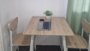 A small dining area with a wooden table, two chairs, a laptop, a mouse, and a potted plant. A framed sign on the wall reads "GOOD VIBES ONLY". - Birmingham Luxury House - Modern Retreat (Birmingham)