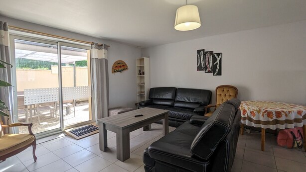 Una sala de estar con un sofá, una mesa de centro y una mesa de comedor con mantel de flores.