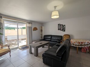 Un salon avec un canapé, une table basse et une table à manger recouverte d’une nappe à motifs floraux.