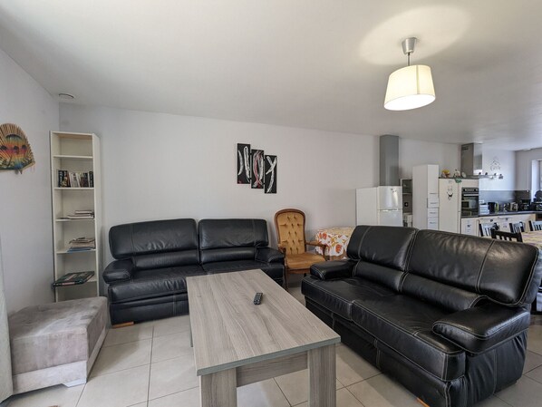 A modern living room with a sectional sofa, a coffee table, and a bookshelf.