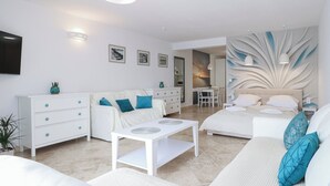 A modern, well-lit living room with a sofa, a dining area, and a bedroom with a large bed and decorative wall. - Morski Anioł by Baltic Home (Swinoujscie)