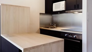 Una cocina moderna con encimera de madera, electrodomésticos de acero inoxidable y armarios oscuros.