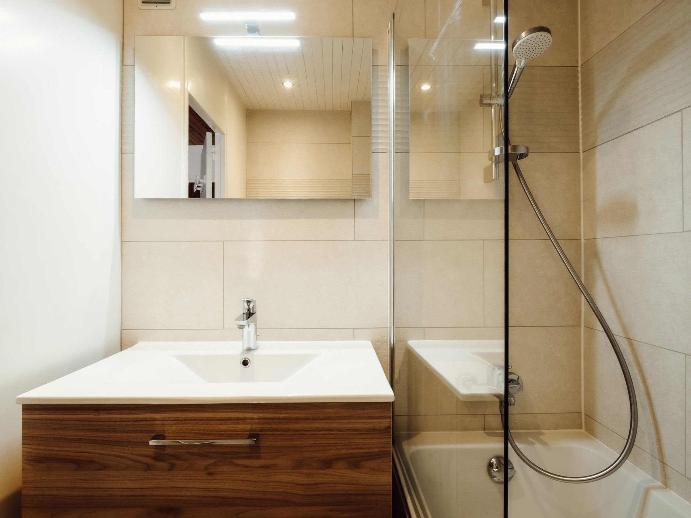 A bathroom with a wooden vanity, a mirror, a shower, and a bathtub.