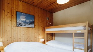 Una habitación de madera con literas, un cuadro en la pared y una lámpara de noche.