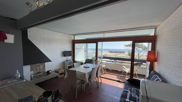 A modern kitchen with a dining area, a fireplace, and a view of the beach. - Saint-Cyprien: Cozy seafront T2 with parking and pets allowed (Saint-Cyprien)