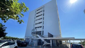 A modern building with a staircase leading to an upper level, a covered pedestrian walkway, and a parking area with cars. - Saint-Cyprien: Cozy seafront T2 with parking and pets allowed (Saint-Cyprien)
