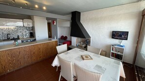 A modern kitchen with a central island, a dining area with a table and chairs, and a living area with a TV and bookshelf. - Saint-Cyprien: Cozy seafront T2 with parking and pets allowed (Saint-Cyprien)