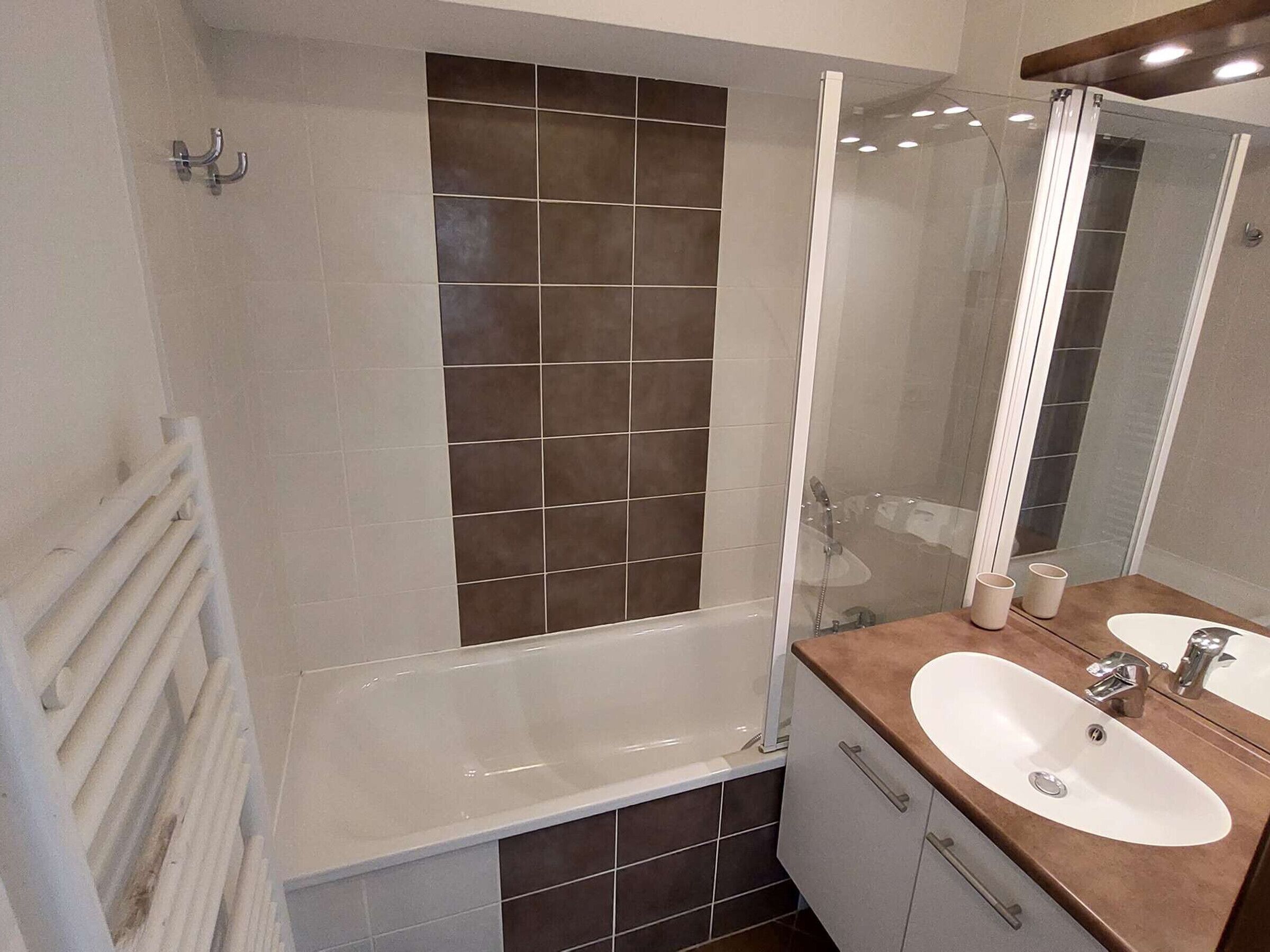 A bathroom with a bathtub, a sink, and a mirror.