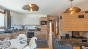 A modern kitchen with white cabinets, a dining area with a marble table, and a cozy seating area with a fireplace. - New duplex, near slopes, 8 pax, parking (Huez)