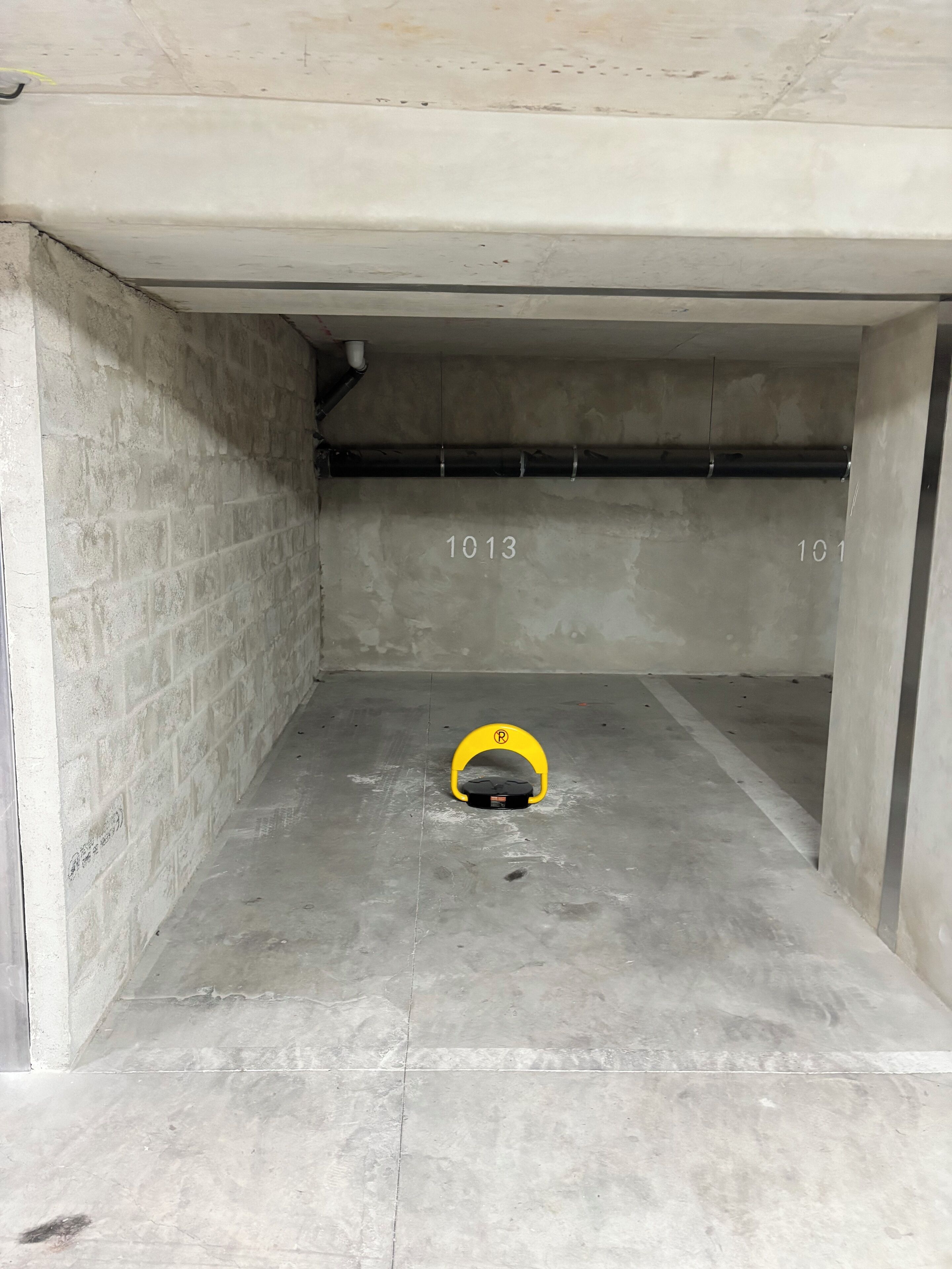 A parking garage with concrete walls, numbered parking spots, and a yellow parking sign.