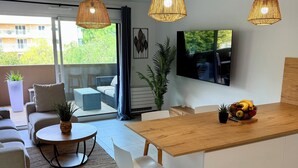 Une cuisine moderne avec un plan de travail en bois, un coin repas avec une table ronde et des chaises, et un salon avec un canapé et un téléviseur.