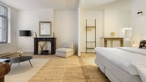 A modern bedroom with a fireplace, a sofa, a bed, and a TV. - Junior Suite in The Heart of Antwerp (Antwerpen)