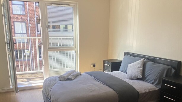 Un dormitorio con cama, mesitas de noche y vistas a un balcón.