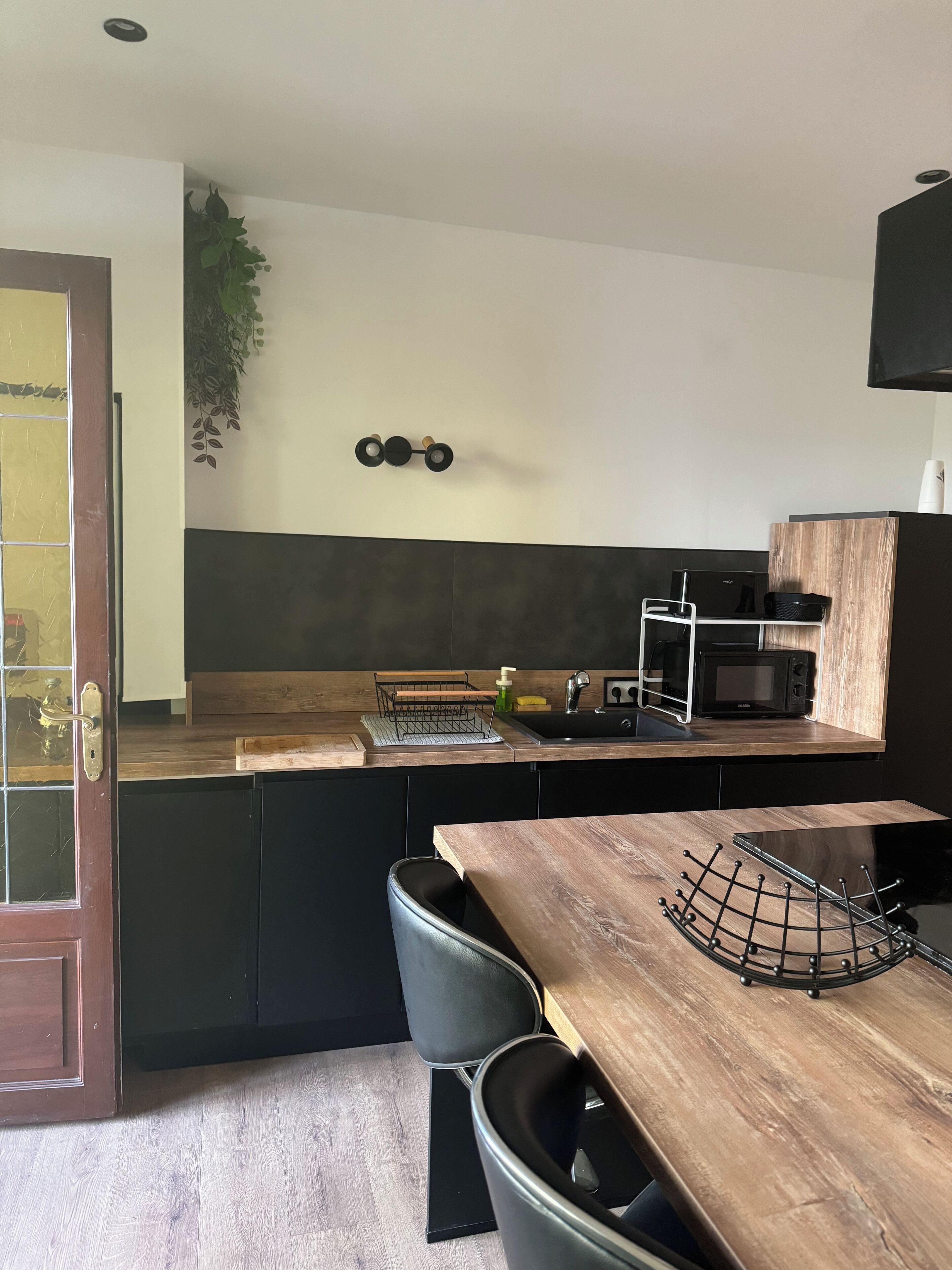 Een moderne keuken met een houten aanrecht, een spoelbak, een magnetron en een zwart kastje.