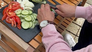 A person preparing a meal on a wooden table outdoors. - Magical Forest Dome Getaway (Vestland)