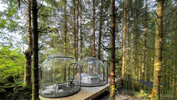 Two transparent dome structures with seating and tables, set on a wooden platform in a forest. - Magical Forest Dome Getaway (Vestland)