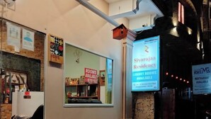 Un hall d’hôtel comprenant un comptoir d’accueil, un panneau indiquant les chambres disponibles et un écran numérique faisant la publicité des chambres de luxe de l’établissement Sivaraja Residency.