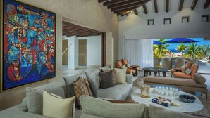 Un amplio salón con un cuadro abstracto grande, asientos cómodos y vista al océano.
