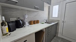 A kitchen with a marble countertop, a wine bottle, a coffee maker, and three wooden containers labeled coffee, sugar, and tea. - 137 AN - Stay ZEA Studio (Ayia Napa)