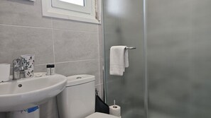 Ein Badezimmer mit weißem Waschbecken, Toilette und Duschkabine aus Glas.