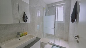 Ein modernes Badezimmer mit einem großen Waschbecken, Toilette und Duschbereich.