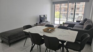 Ein modernes Wohnzimmer mit Esstisch, Sofa und Fernseher.