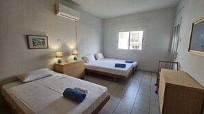 Un dormitorio con dos camas, un aparador, un escritorio y un equipo de aire acondicionado.