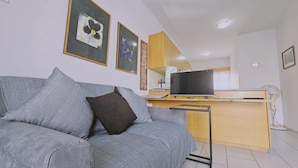 Una sala de estar con un sofá gris, un televisor de pantalla plana y un mueble de madera.