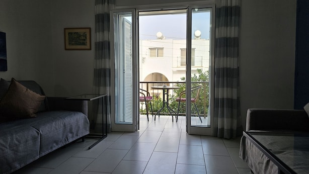 Habitación de hotel moderna con sofá, una mesita y balcón con vistas a edificios.