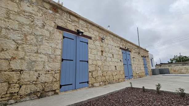 A stone building with two blue doors and a small garden area with plants.