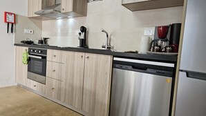 A modern kitchen with a dishwasher, oven, and a coffee maker.