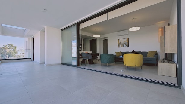 A modern living room with a glass door leading to a dining area, a sofa, and a coffee table. - 132 LCA - Stay Diamond Apartment (Larnaca)