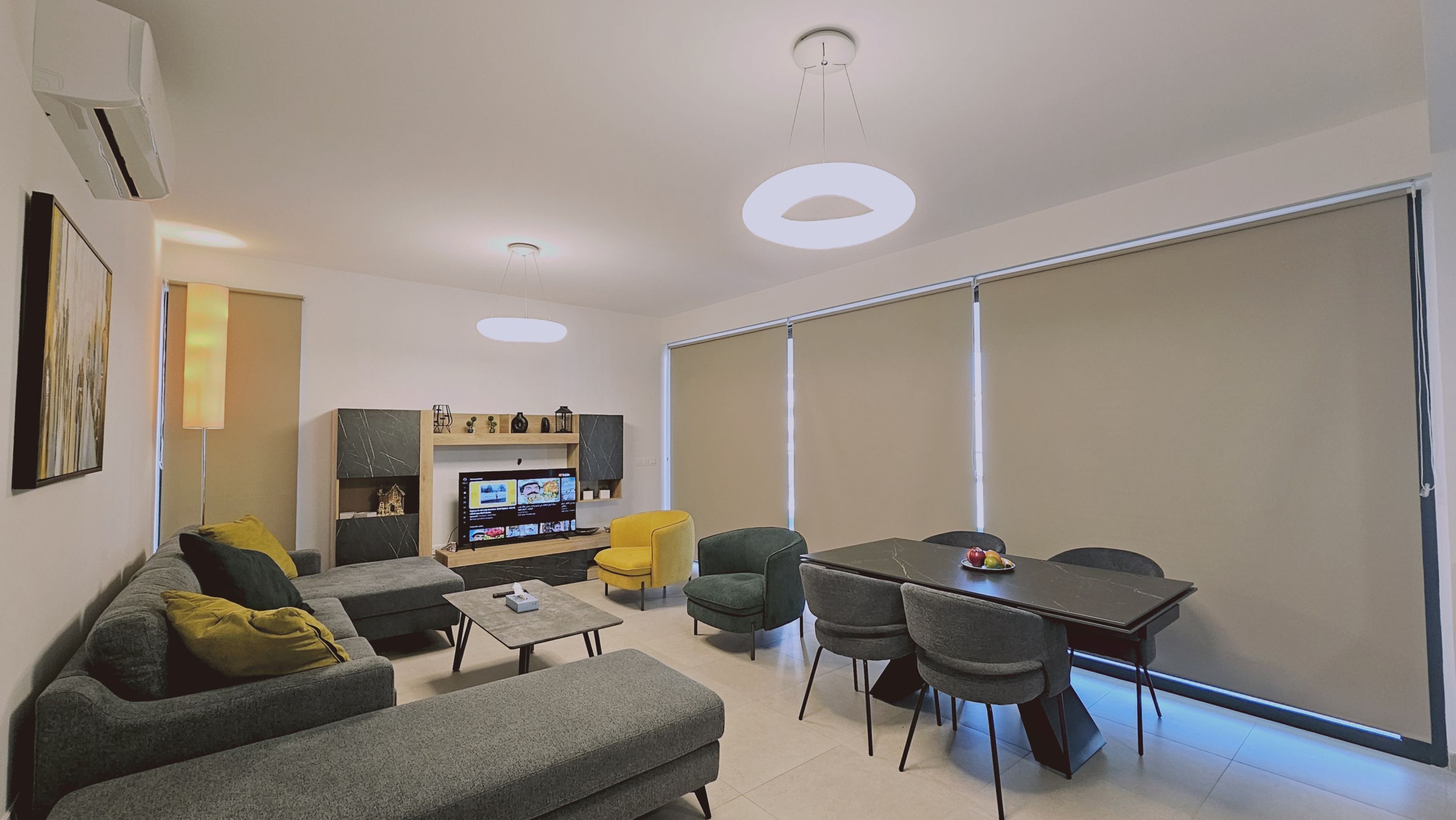 A modern living room with a sofa, chairs, a coffee table, a TV, and a sliding door.