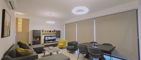 A modern living room with a sofa, chairs, a coffee table, a TV, and a sliding door.