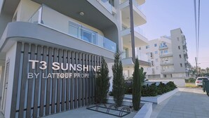 Ein modernes Apartmenthaus mit Balkonen, einem verschlossenen Eingang und blauem Himmel.